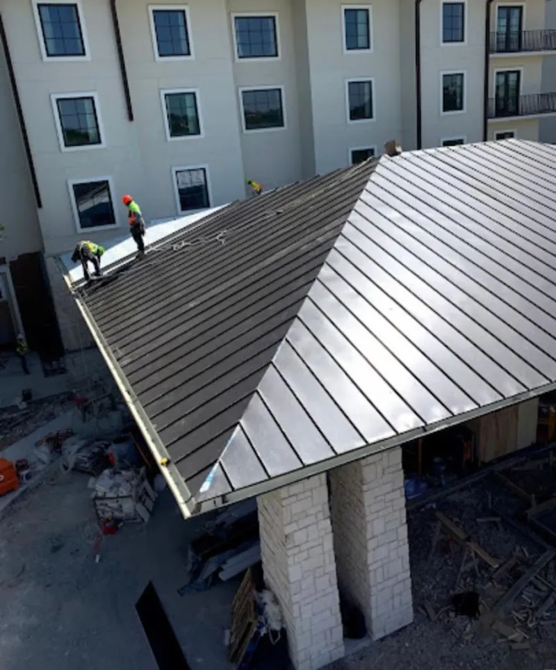 Crew installing standing seam metal roof panels on a commercial project in Braselton
